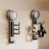 A pair of modern, silver suction cup hooks with a rotating head mounted on a beige wall.