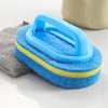 Blue and yellow sponge cleaning brush with a blue handle resting on a gray cloth.