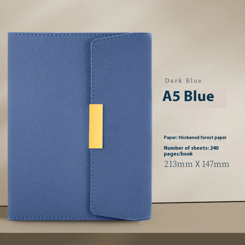 A dark blue A5 journal notebook with a gold-colored closure tab shown on a light brown background.
