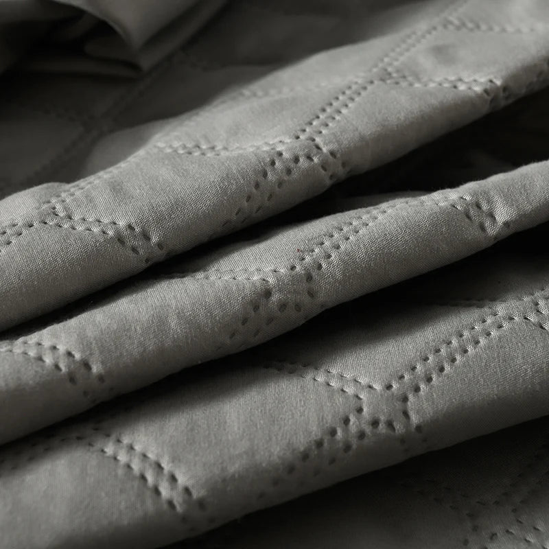 Close-up of a gray quilted waterproof mattress protector with deep pockets.