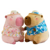 A pink capybara plush toy wearing a straw hat and a blue patterned swim top.