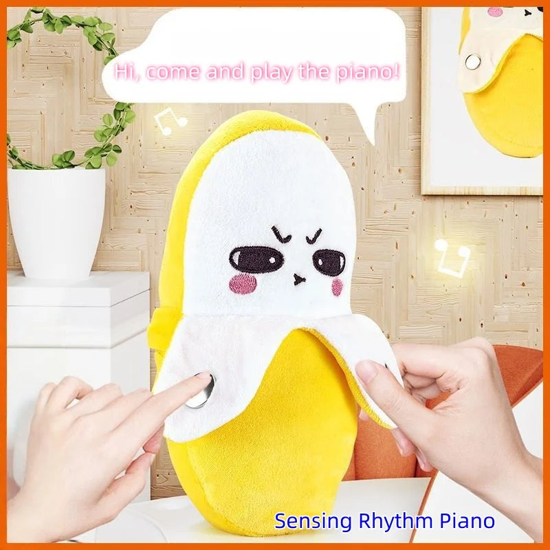 A yellow banana-shaped plush toy with expressive eyes is shown next to a hand, demonstrating the Sensing Rhythm Piano.