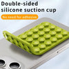 A double-sided silicone suction cup pad in lime green is shown being used to mount a phone on a silver device.
