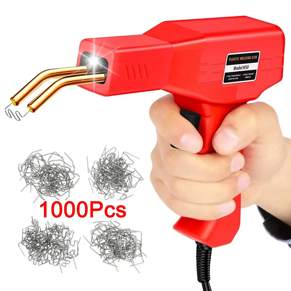 A hand holds a red plastic welding gun with a gold tip, next to several bundles of metal wire.
