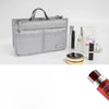 A silver purse organizer insert with multiple compartments and a handle, shown next to various cosmetic products.