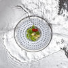 A close-up view of a universal silicone sink drain filter strainer with fresh herbs and chili placed inside.