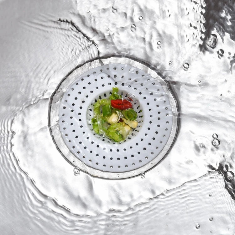 A close-up view of a universal silicone sink drain filter strainer with fresh herbs and chili placed inside.