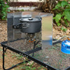 A portable aluminum alloy windshield is shown mounted on a camping stove setup.