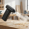 A black high-speed cordless air duster is shown blowing compressed air onto a wooden surface, creating dust and debris.