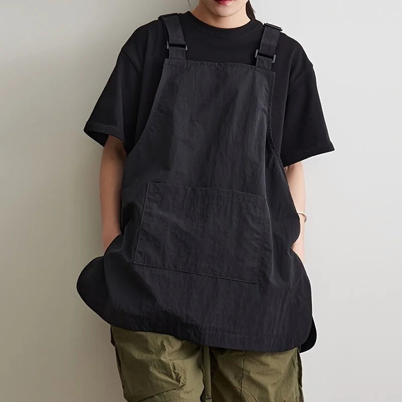 A person wearing a black waterproof work apron over a black t-shirt and olive green pants.