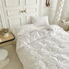 White luxury duvet cover set with a 3D twist floral pinch-pleated pattern displayed on a bed.