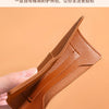 A close-up shot of a brown leather passport holder or card case being held by a hand.