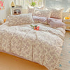 A floral duvet cover set in beige and pink tones with a matching flat sheet and pillows on a bed.