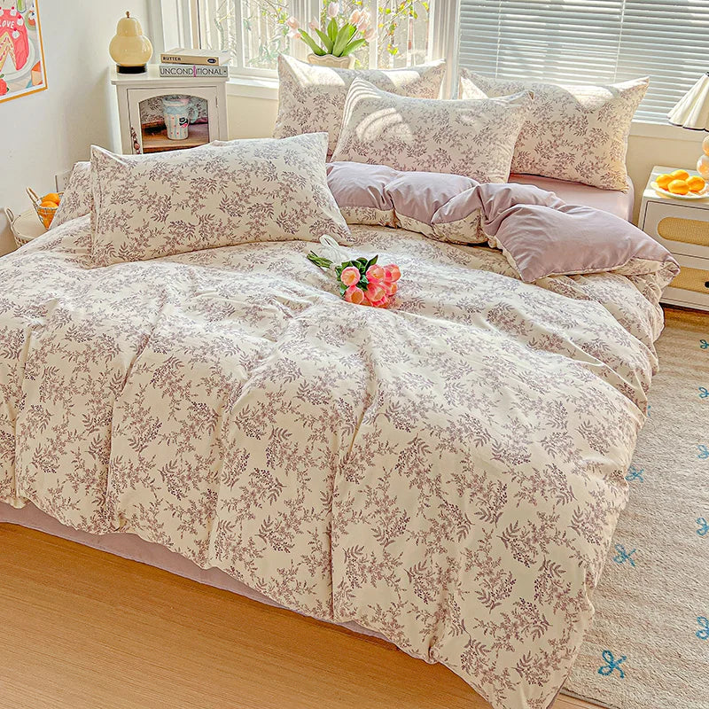 A floral duvet cover set in beige and pink tones with a matching flat sheet and pillows on a bed.