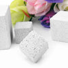 White natural mineral molar stones for small pets scattered on a white surface with pink and purple flowers in the background