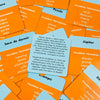 A close-up of a box of orange and yellow cards for the Name That Word Spanish Edition card game