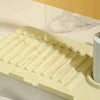 A silicone faucet draining mat with a manifold design is shown dripping water into a sink.