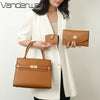 A woman holds a tan leather handbag and a matching coin purse next to a white blazer.