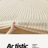 A close-up of a cream colored faux fur fitted sheet being touched on a bed.