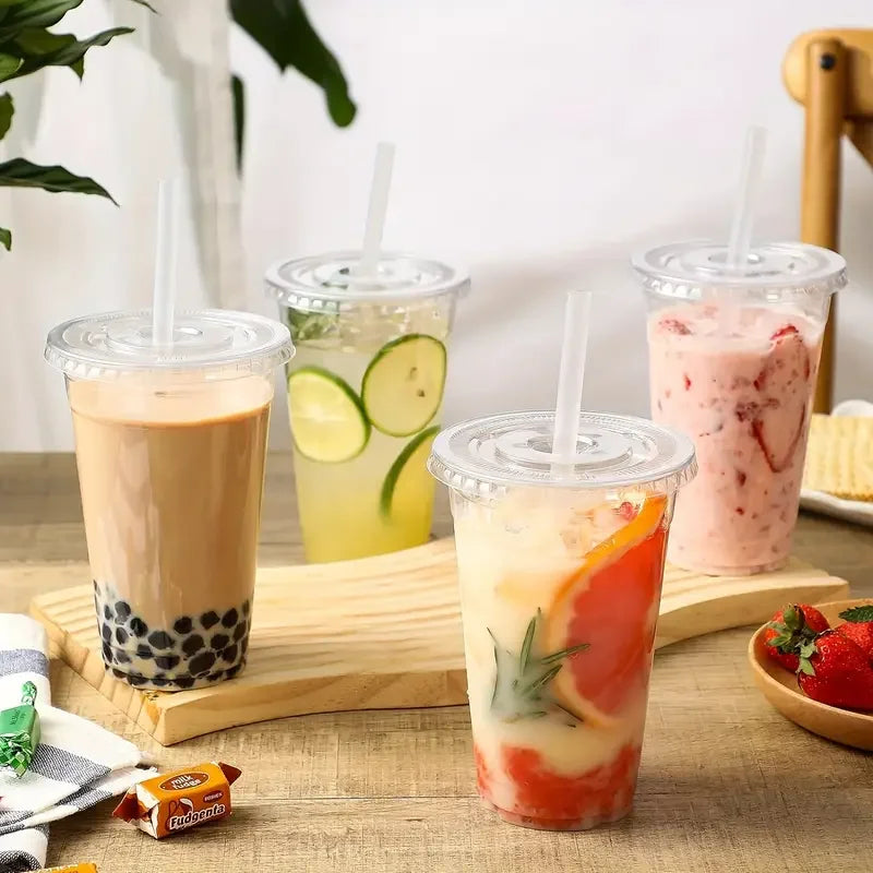A glass of iced fruit drink in a clear plastic cup with a straw, placed on a wooden board.