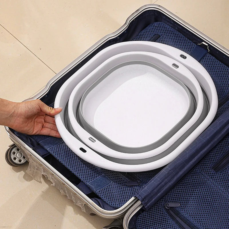 A hand is placing a white foldable plastic wash basin into a blue fabric storage bag.
