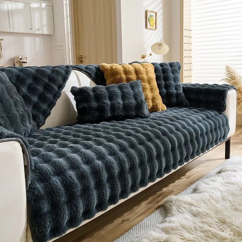 Dunkelgraues Plüschkaninchen-Sofa-Kissen mit strukturiertem Stoff und gelben Akzenten auf einem weißen Sofa.