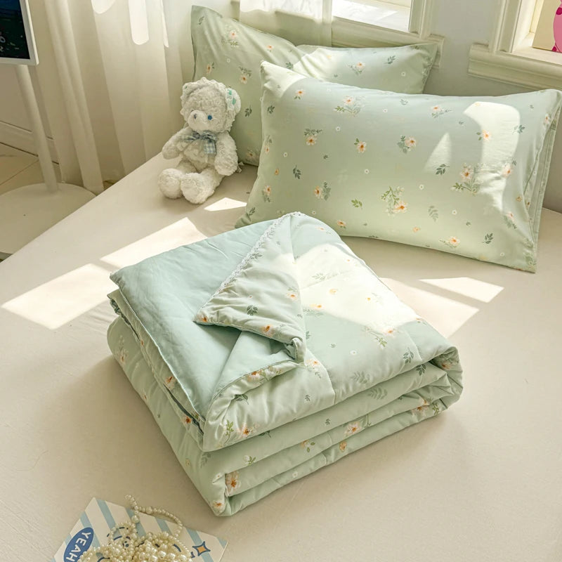 A light mint green lace-trimmed duvet and pillows with floral embroidery displayed on a white surface.