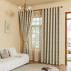 A set of beige and white plant pattern blackout curtain panels hanging in a room with a window.