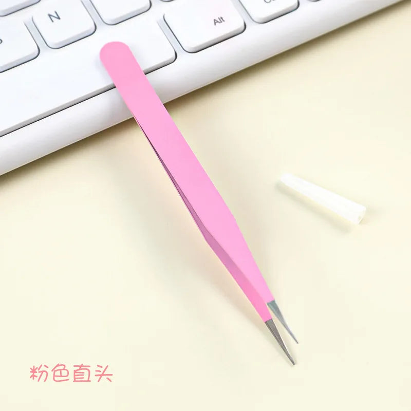 A pink precision craft tool with a straight tip is placed on a light surface next to a white object and a keyboard.