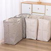 Three striped laundry baskets in beige and gray fabric lined up on a wooden floor.