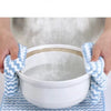 Blue microfiber cleaning cloths being used to insulate and protect a white bowl from hot liquid.