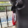 A black keychain with a red tag reading SLOW CAR CLUB attached to a car door handle.