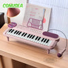 A pink electronic keyboard piano with a microphone and stand is displayed on a wooden desk.