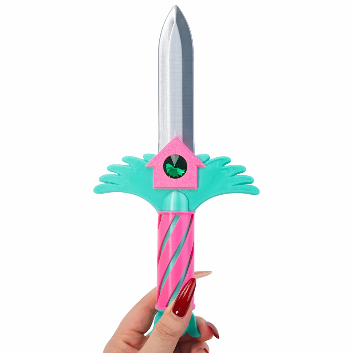 A pink and teal dagger key necklace with a green gemstone and a silver blade, held by a hand.
