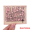 Pink letter embroidered patch spelling MAKE HEAVEN CROWDED on a beige fabric background