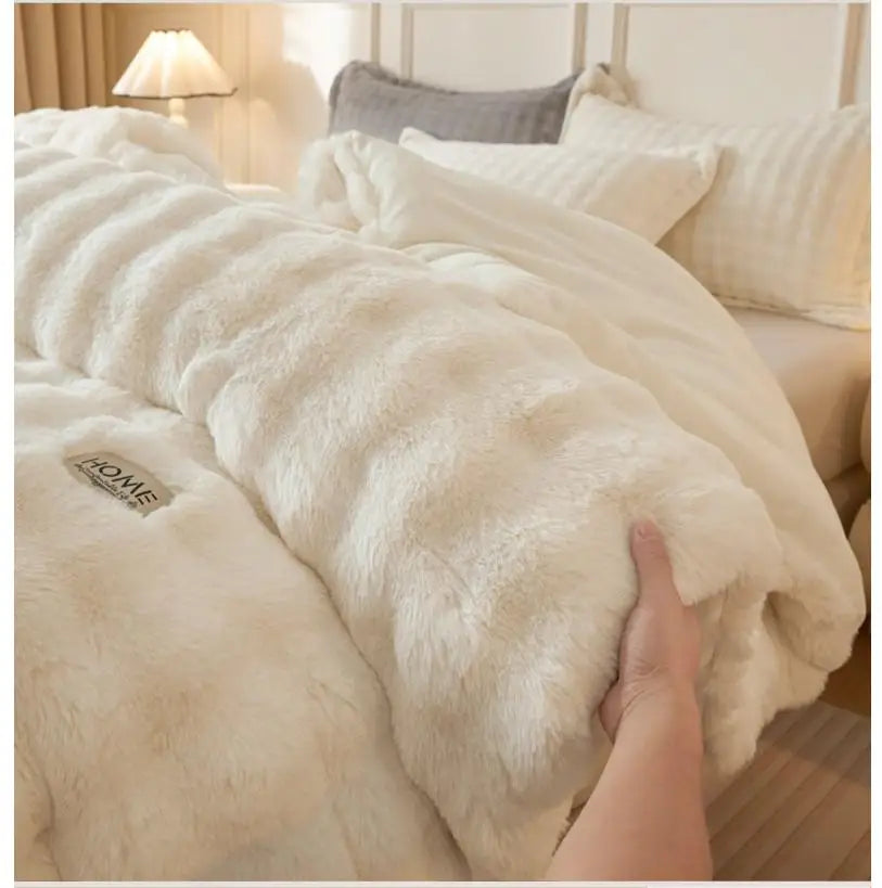 A close-up of a thick, cream-colored faux fur comforter draped over a bed.