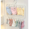 A white laundry drying rack with multiple hanging clips holding various colored baby bodysuits and tops.