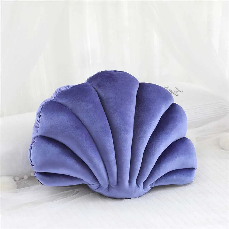A soft lavender velvet shell print throw pillow resting on white bedding.