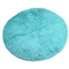 A round, light turquoise shaggy rug with a fluffy texture.