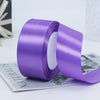 A roll of vibrant purple satin ribbon used for gift wrapping or DIY crafts.