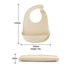 A beige silicone baby bib with a catch pocket and a separate thin silicone piece shown in various dimensions.