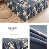 Un jupon de lit bleu marine imprimé avec des motifs floraux blancs et jaunes sur un lit.