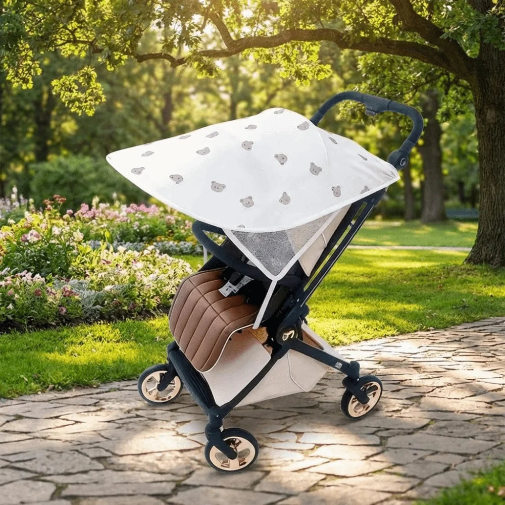 A beige and black stroller with a white sun shade is parked on a stone path under a large tree.