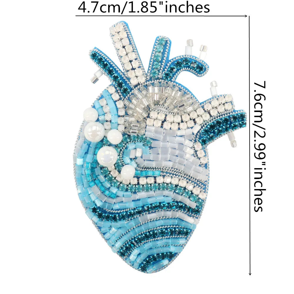 A sparkling blue and clear beaded rhinestone patch shaped like a heart for clothing and DIY crafts.