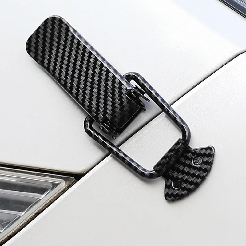 Black carbon fiber rear trunk locking buckle set mounted on a white car panel.