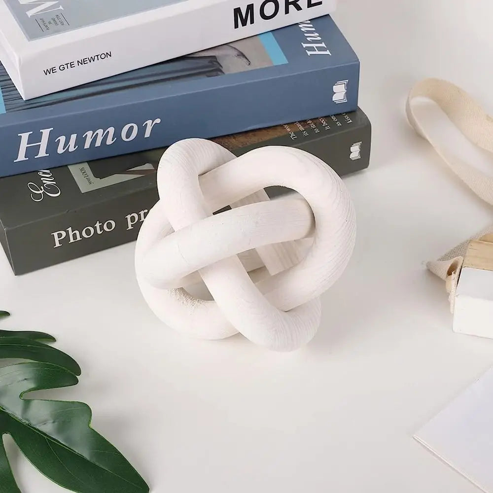 A white, hand-knotted rope decor item is displayed next to several boxes of humor and photo prints.