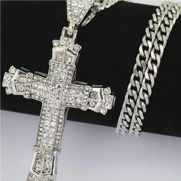 Pendentif croix en strass argentés sur chaîne argentée, présenté sur fond noir.