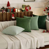 A collection of olive green and white textured throw pillow covers displayed on a sofa with wooden decor.