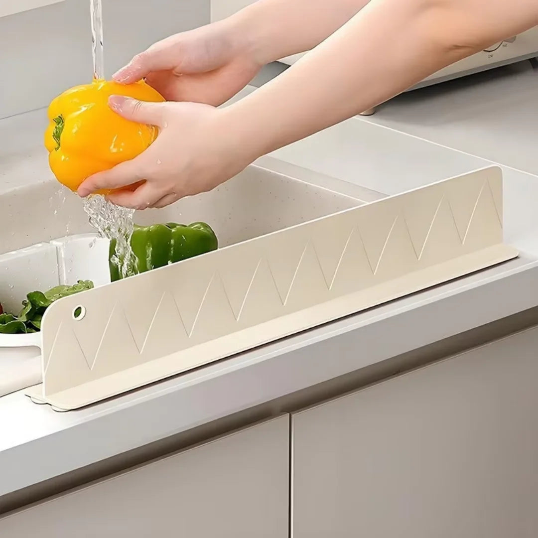 A hand is rinsing a yellow bell pepper under a flexible silicone sink splash guard.
