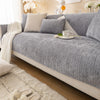A gray geometric sofa cushion cover with white throw blanket and decorative pillows on a light-colored sofa.